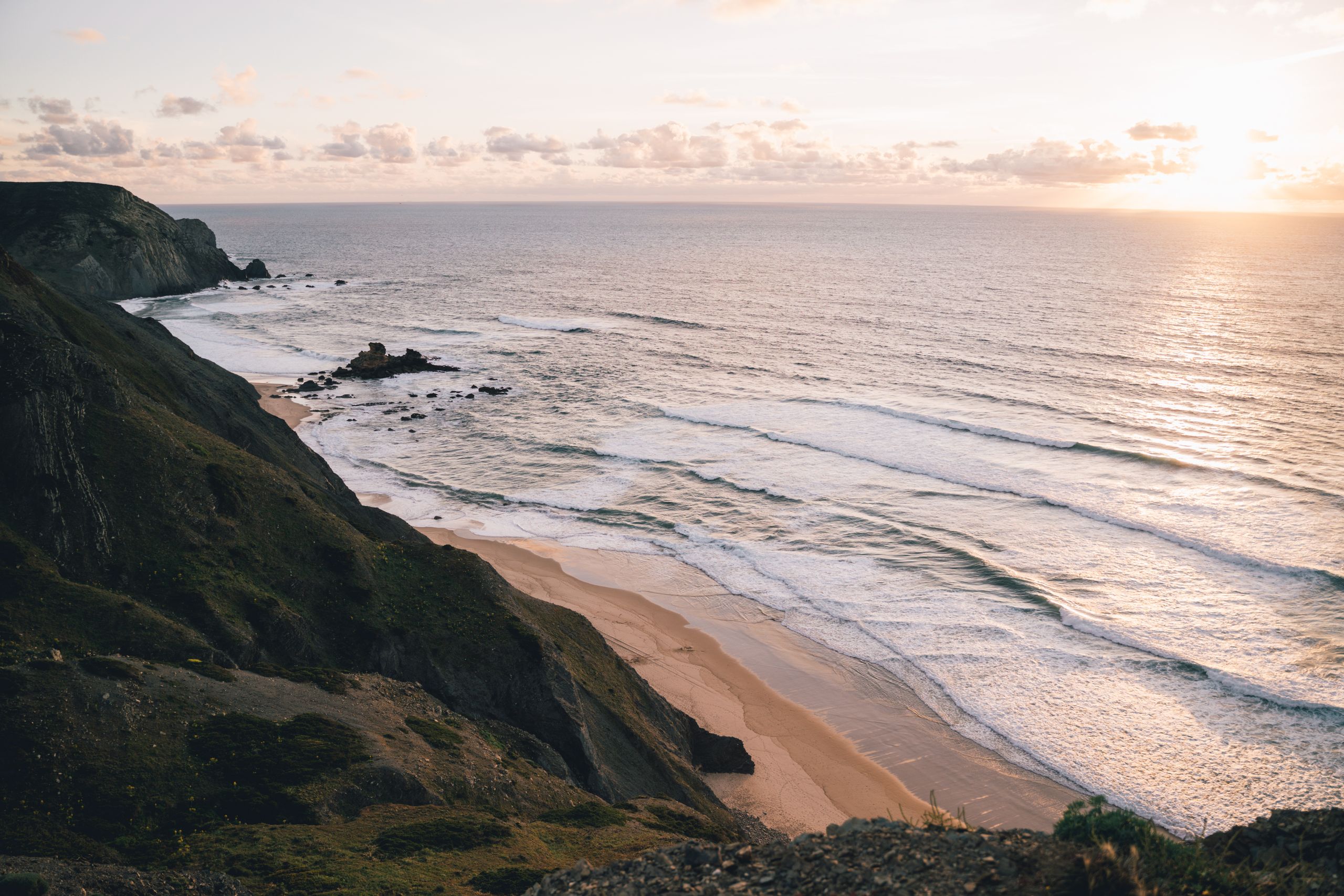 Breathtaking view of Portugal's rugged coastline at sunset, with waves crashing against the rocky shore.